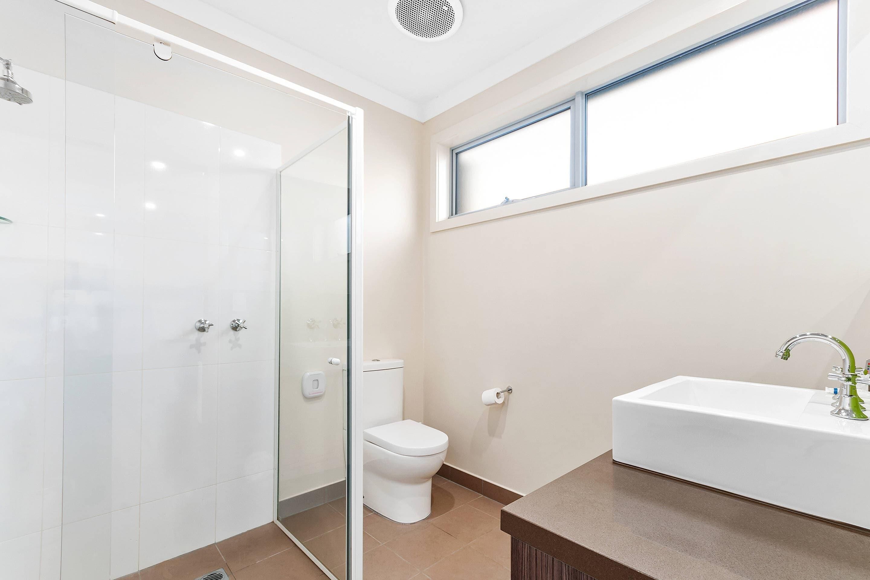 Un baño con cabina de ducha de vidrio, inodoro y lavabo con espejo.