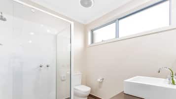 Un baño con cabina de ducha de vidrio, inodoro y lavabo con espejo.