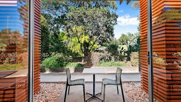 A patio with two chairs and a table, surrounded by a wooden fence and a garden view.