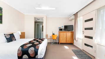 A hotel room with a bed, a desk, a TV, and a wardrobe.
