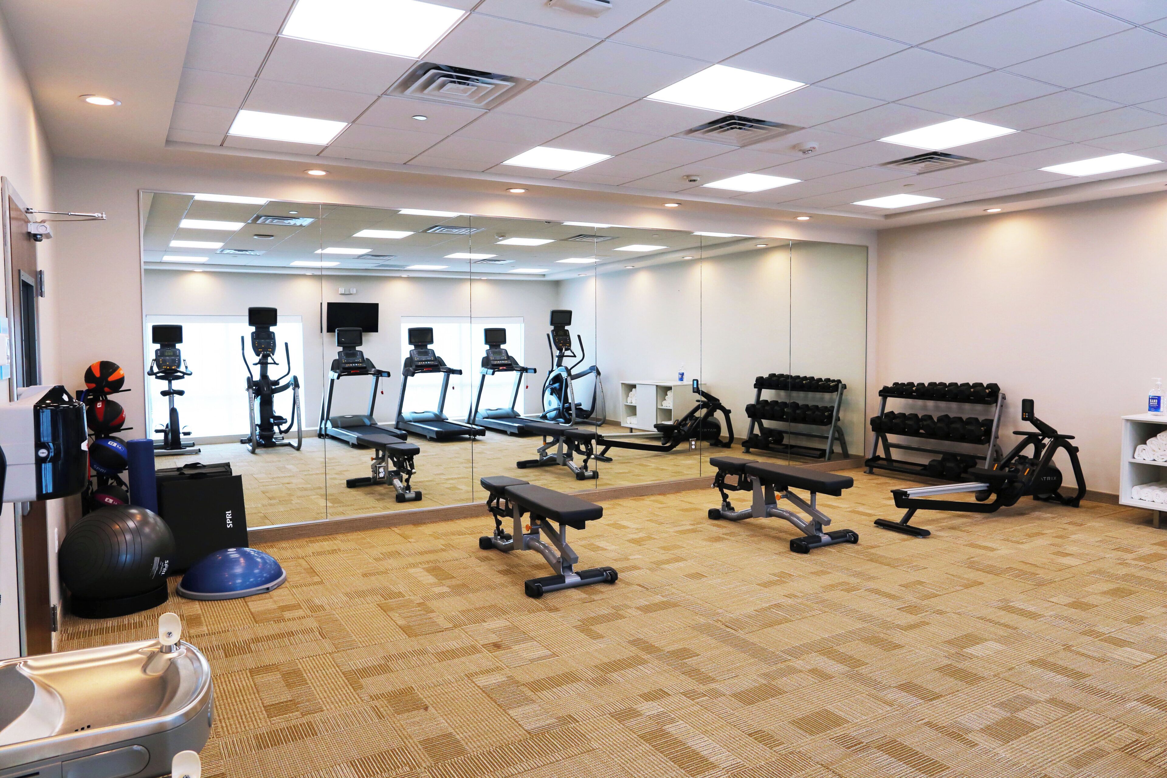 A gym with various exercise equipment, including treadmills, stationary bikes, and weight machines.