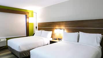 A hotel room with two beds, a large window, a wall-mounted air conditioner, and a bedside table with a lamp.