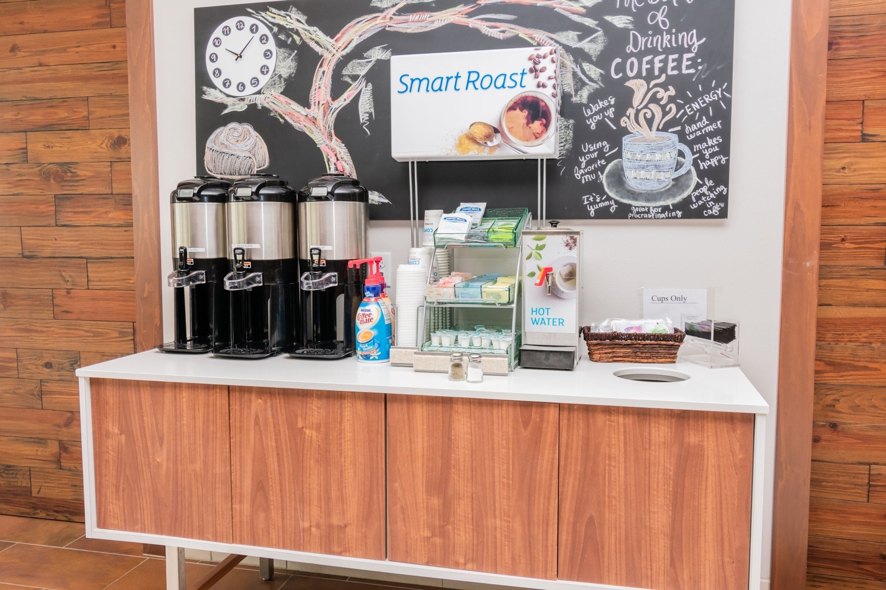 A coffee station with multiple coffee makers, a water dispenser, and a sign that reads "Smart Roast."