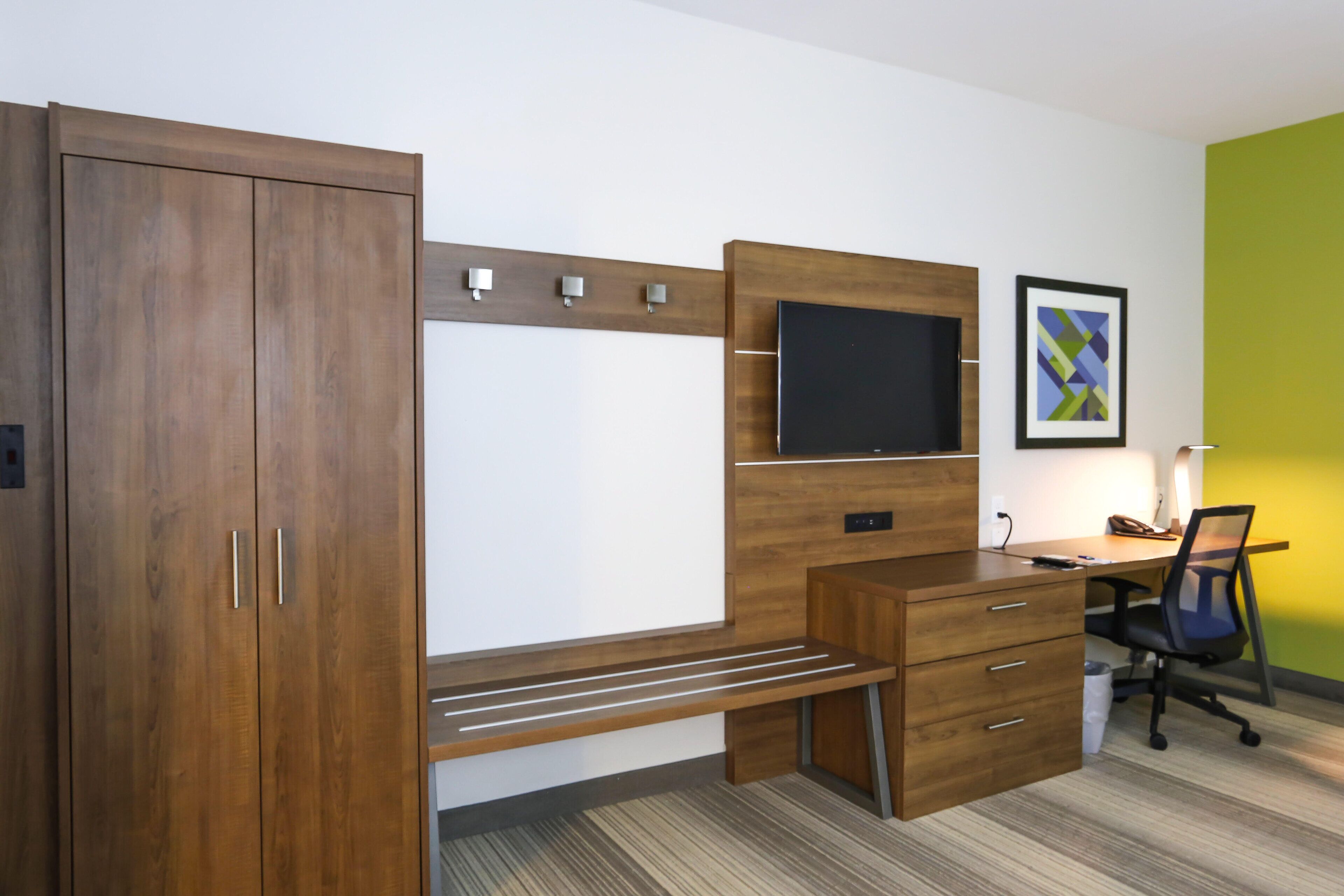 A modern office space with a wooden desk, a mounted flat-screen TV, and a chair.
