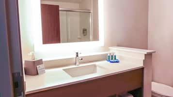 Un baño con lavamanos blanco, un espejo y un dispensador de toallas.