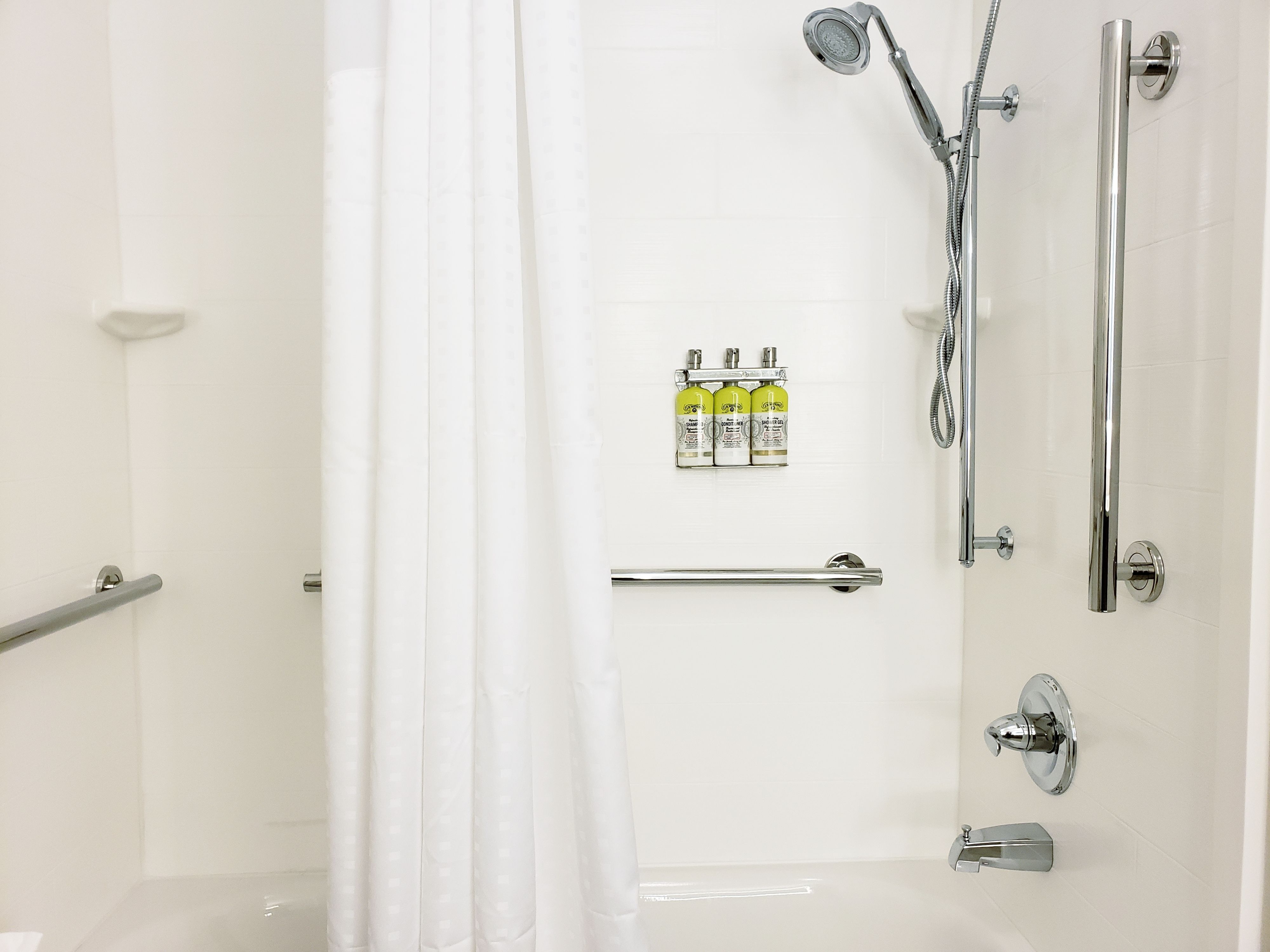 Un baño moderno con ducha, inodoro y barra de apoyo.