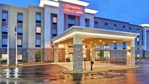 Un hotel Hampton Inn & Suites con una fachada moderna, un acceso cubierto y revestimiento de ladrillo.