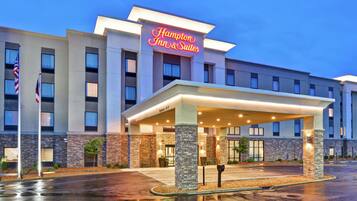 Welcome to Hampton Inn & Suites, featuring a modern architectural design with a flat roof and a mix of brick and stone facade.