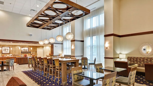 Un vestíbulo de hotel con comedor, muebles de madera y una alfombra estampada.