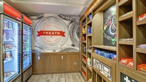 Interior de una tienda con vitrinas refrigeradas para productos, un mural en la pared y estantes llenos de aperitivos.