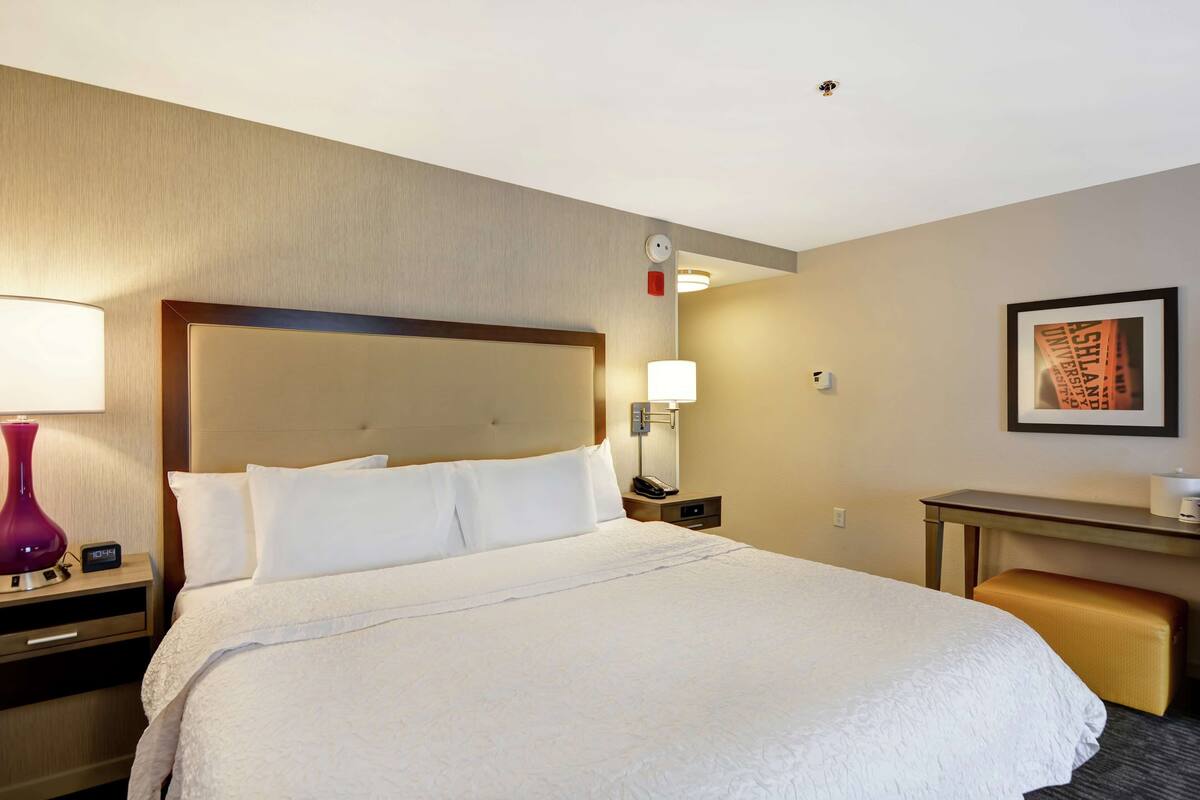 A hotel room with a large bed, bedside tables, a desk, and a chair.