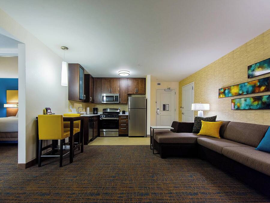 A hotel room with a kitchenette, a dining area, a sofa, and a bed.