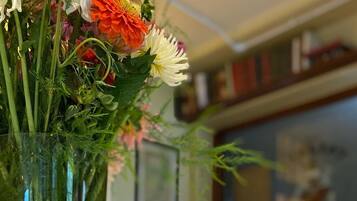 Una mesa con un florero de vidrio transparente que contiene un ramo de flores y dos copas de vino vacías.