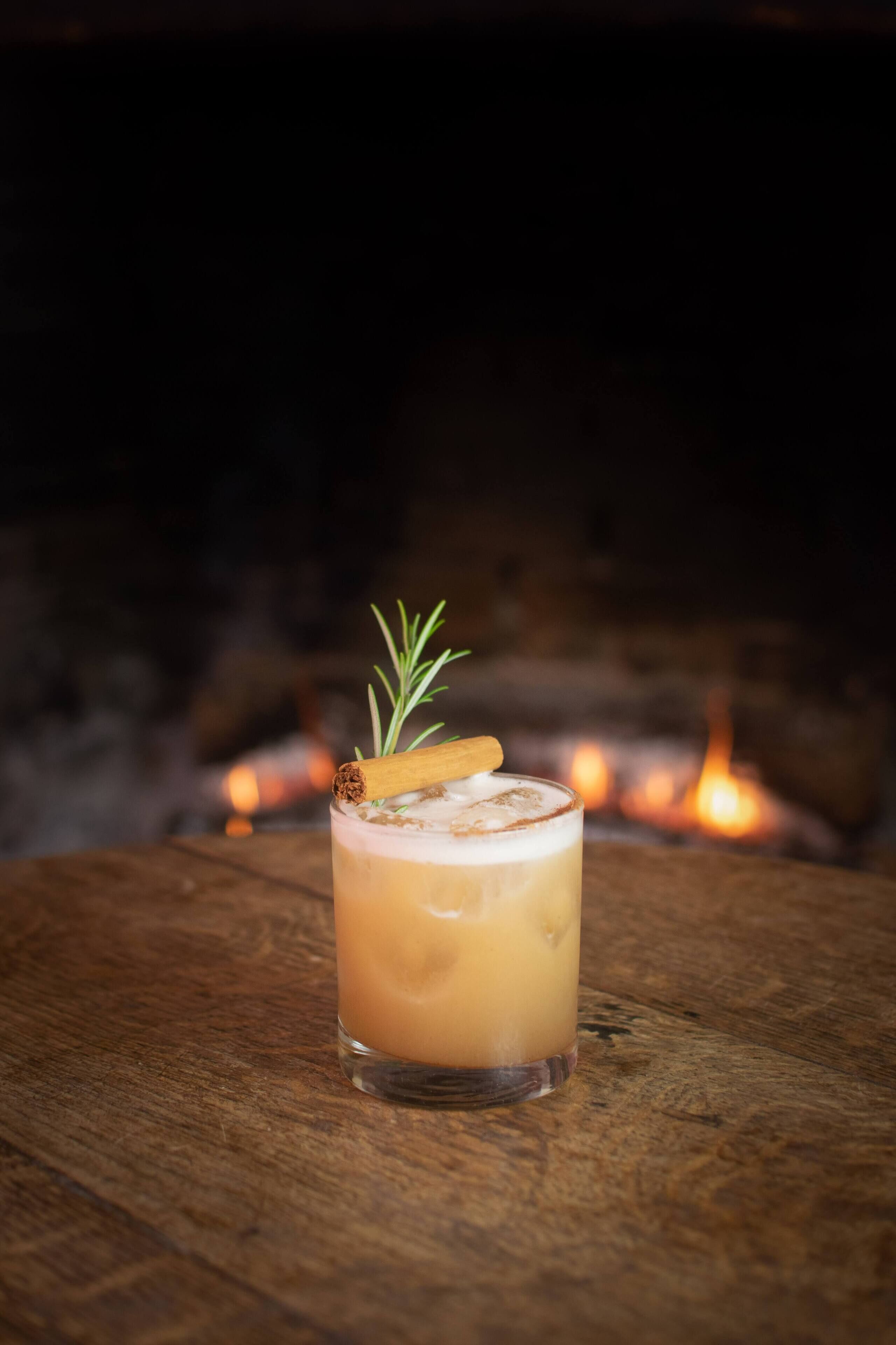 A glass of beverage with a garnish on a wooden surface.