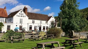 A white building with "THE TALBOT" sign, outdoor seating, and a grassy area. - The Talbot at Knightwick (Worcester)