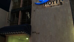 Un hôtel au design moderne, avec un logo bien visible sur la façade et une entrée abritée.