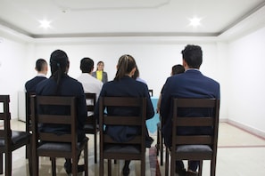 A conference room with wooden chairs arranged in rows facing a table with a blue cloth. - SB Hotel Internacional (Cali)