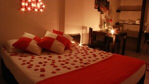 Une chambre d’hôtel avec un lit décoré de pétales de rose et un oreiller à carreaux rouges et blancs.