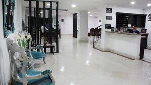 Un espace d’accueil d’hôtel comprenant un comptoir de réception, des chaises et un espace d’attente.