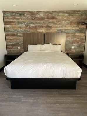 A modern bedroom with a large bed, wooden headboard, and a textured wall. - Hyde Park (Los Angeles)