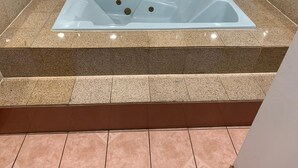 Ein rechteckiges Whirlpool mit Glasabdeckung, umgeben von Granitfliesen.