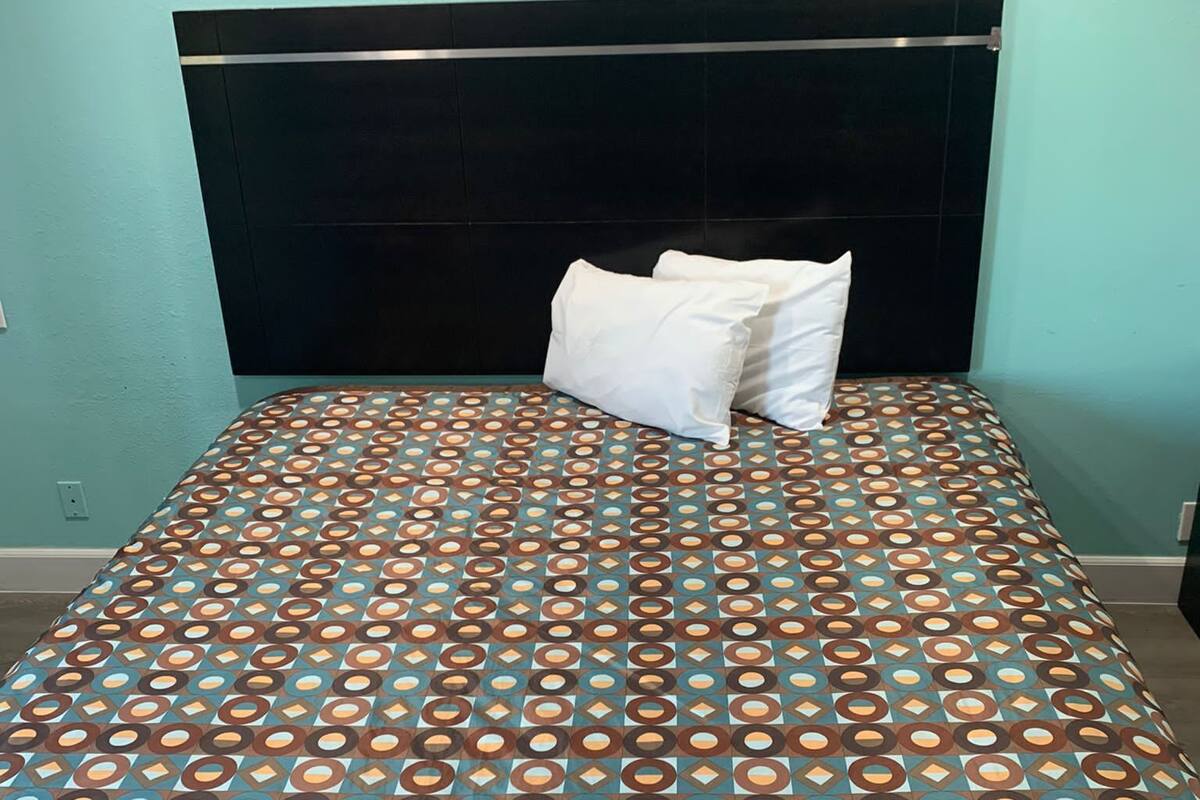 A bed with a patterned bedspread and a black headboard.