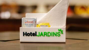Una caja de pañuelos HotelJARDINS con un pañuelo y dos sobres pequeños, uno etiquetado 'Guarani' y el otro 'Endulzante de Mesa'.