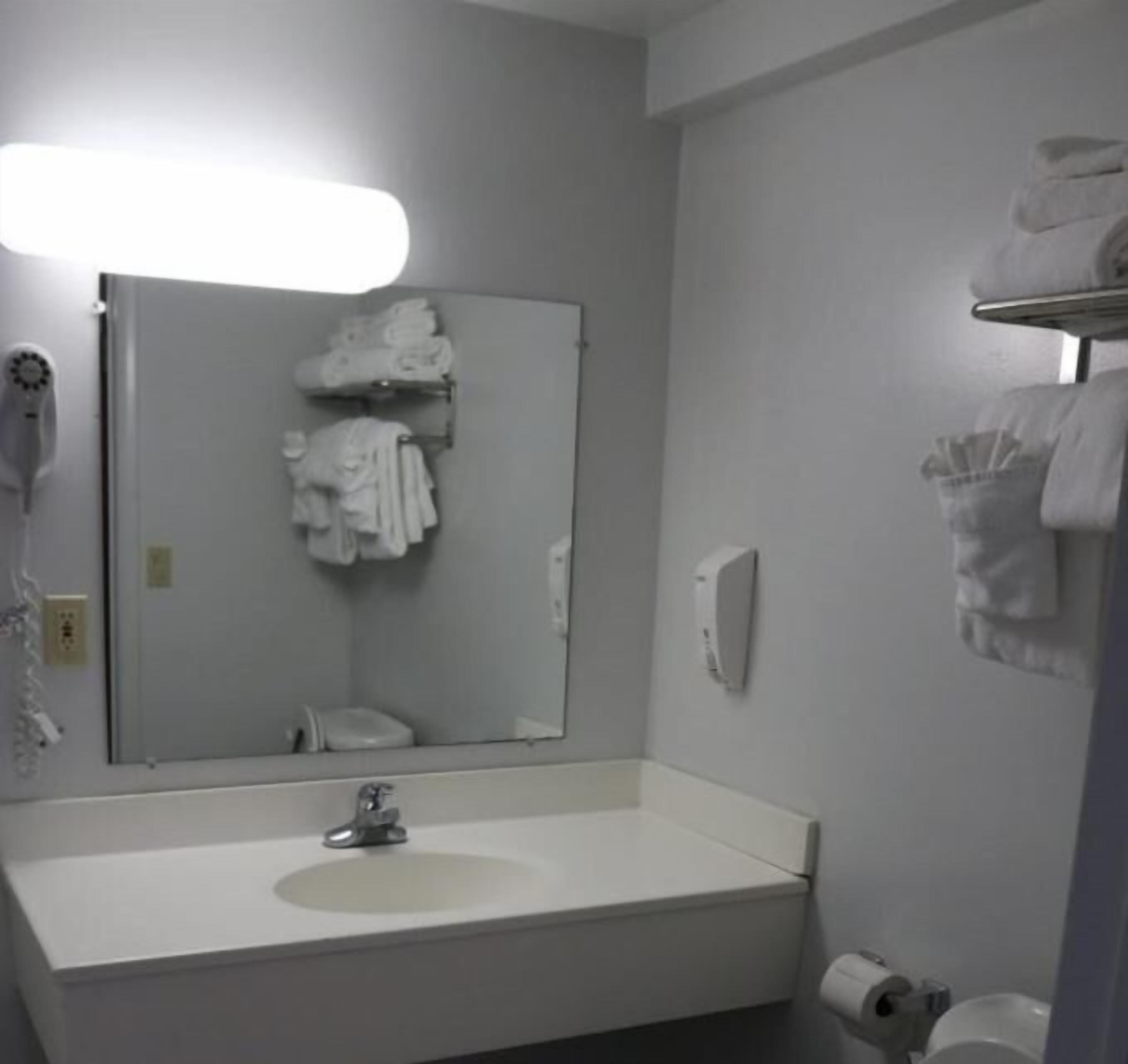 A bathroom with a white sink, a mirror, a towel rack, and a hand dryer.