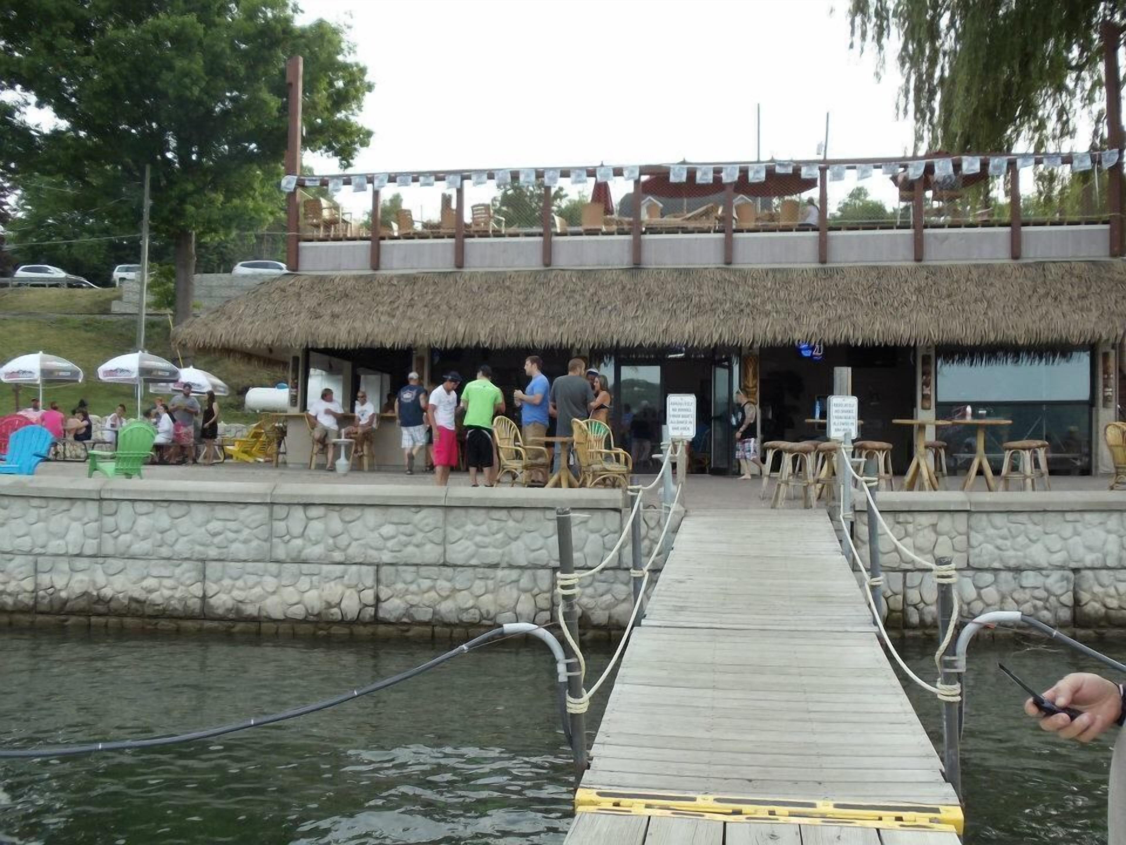 Un muelle de madera que conduce a un edificio con techo de paja y terraza.