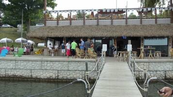 Un muelle de madera que conduce a un edificio con techo de paja y terraza.