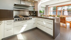 Una cucina moderna con piano cottura a gas, cappa aspirante in acciaio inossidabile e mobili bianchi.