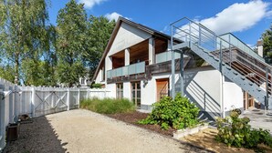 Una moderna casa a due piani con un balcone in legno e una scala che conduce al piano superiore.