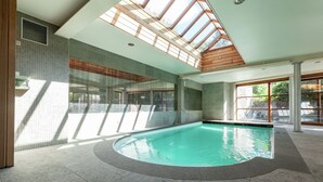 Una piscina interna con lucernario, pareti piastrellate e bordo curvo.