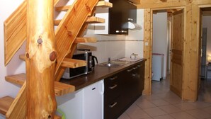 A kitchen with wooden beams, a microwave, a sink, and a refrigerator.