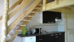 A kitchen with wooden beams, a microwave, a coffee maker, and a sink.