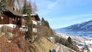 A wooden chalet with a view of a snowy mountain range and a town below. - Apartment in Stuhlfelden near Ski Lift (Stuhlfelden)