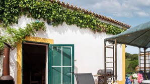 Terrassa exterior amb taula preparada per dinar, una barbacoa i una zona de seients coberta.