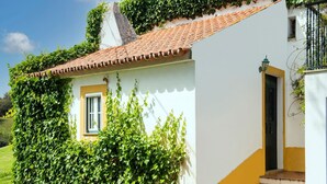 Edifici blanc amb una part inferior groga, un teulat de rajoles i una finestra petita.