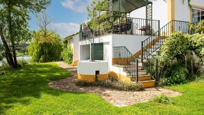 Una casa de dues plantes amb un balcó, una escala i un jardí.