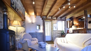 A cozy room with a stone fireplace, a sofa, a table, and a kitchen area. - Holiday Home in Gramat with Private Pool (Gramat)