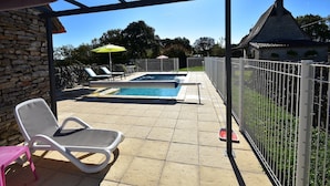 A pool area with two pools, lounge chairs, and a stone wall. - Holiday Home in Gramat with Private Pool (Gramat)