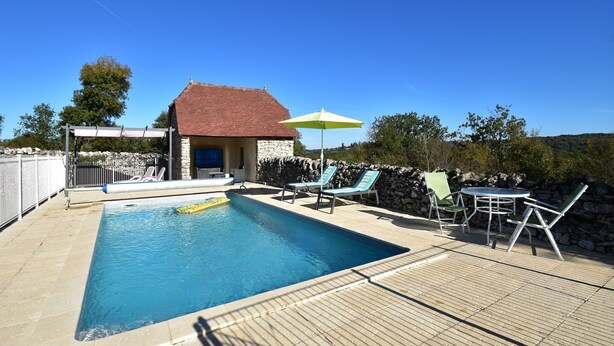 A swimming pool with lounge chairs and an umbrella, surrounded by a stone wall and a stone building. - Holiday Home in Gramat with Private Pool (Gramat)