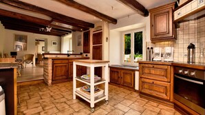 A kitchen with wooden cabinets, a tiled backsplash, and a large window. - Fine group house with sauna garden (Chiny)