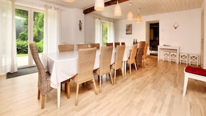 A dining area with a long table, wicker chairs, and hanging light fixtures. - Fine group house with sauna garden (Chiny)