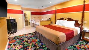 Una habitación de hotel con cama con dosel, microondas, refrigerador, baño y una alfombra colorida.