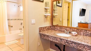 A bathroom with a marble sink, a large mirror, and a shower. - Pacifica Motel (Long Beach)
