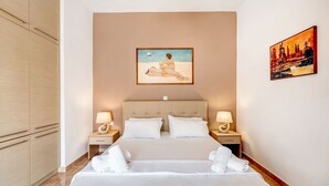 Quarto de hotel com uma cama grande, duas mesas de cabeceira com luminárias, um quadro na parede e um guarda-roupa.