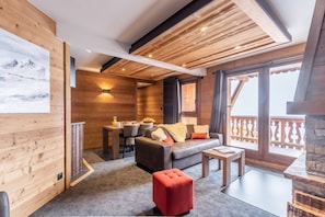 L’intérieur chaleureux d’un chalet avec des murs en bois, un canapé, un coin repas et un balcon doté d’une balustrade.