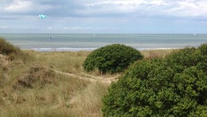 A coastal landscape with dunes, shrubs, and a view of the sea with sailboats. - Oostduinkerke Forestside Villa (Oostduinkerke)