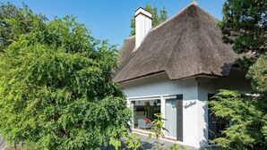 A house with a thatched roof, surrounded by lush greenery. - Oostduinkerke Forestside Villa (Oostduinkerke)